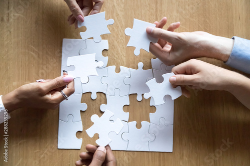 Top view of diverse people assemble jigsaw looking for solution photo