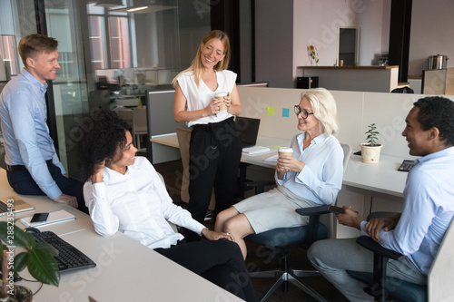 Smiling employees talk at informal meeting in open space