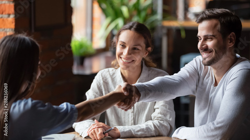 Canvas-taulu Smiling couple making successful deal, handshaking with realtor