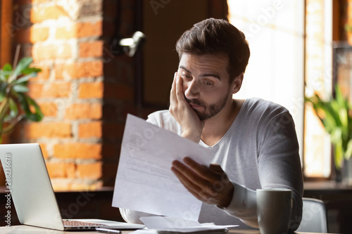 фотографія Confused frustrated man reading letter in cafe, receiving bad news