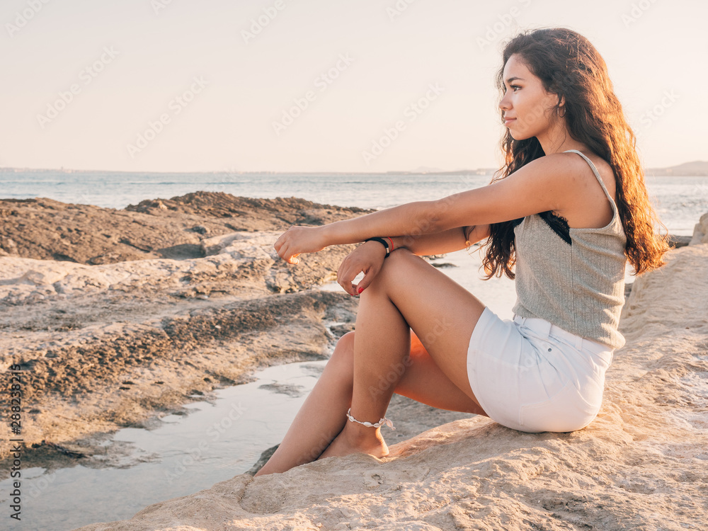 Pretty trendy young ethnic woman on beach at sunset Pretty trendy young ethnic woman on beach at sunset