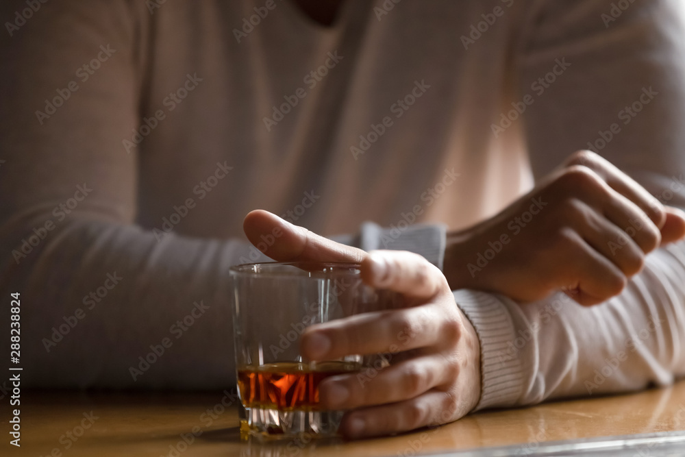 Close up man holding glass with alcohol in hand, drinking alone - obrazy, fototapety, plakaty 