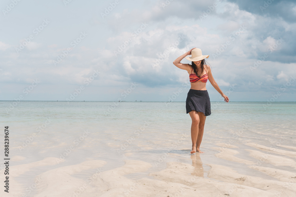 NUNGWI, Zanzibar, Tanzania: woman wearing a sun hat walking on the beach with low tide. NUNGWI, Zanzibar, Tanzania: woman wearing a sun hat walking on the beach with low tide.