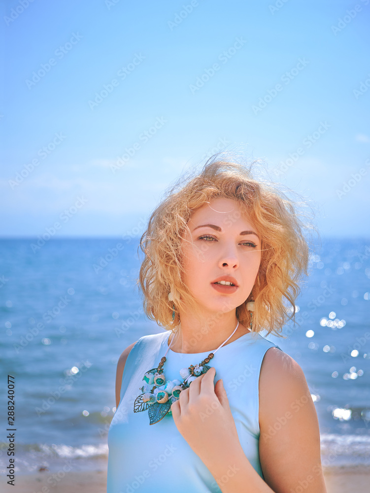 Glamor blondy woman in cyan dress on the beach