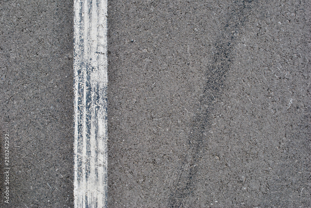 Fototapeta premium Asphalt texture with white line and tire marks . Top view