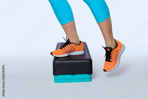 Woman do exercise on a black-turquoise fitness step.