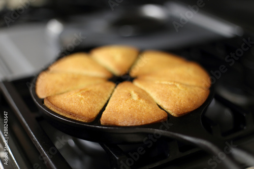 Fresh cornbread from the oven baked in a cast iron wedge pan, resting on top of the stove.