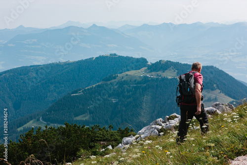 An old man in backpack looks at the alpine mountains. Summer day © Orlovskaya