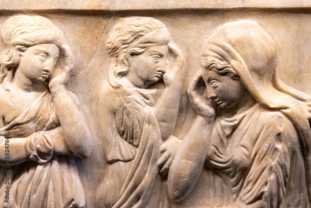 Ancient carved statues on marble showing group of women thinking