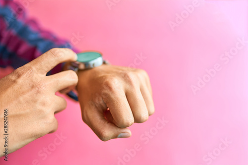 Man wear smart watch in everyday lifestyle with blank screen. He using smart watch Pink background