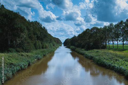 Kanal in Holland mit Wald und Wolken