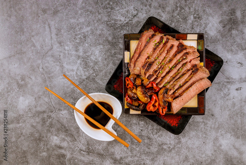 Chinese style sliced roast beef steak mushrooms sesame seeds, soy sauce with chopsticks