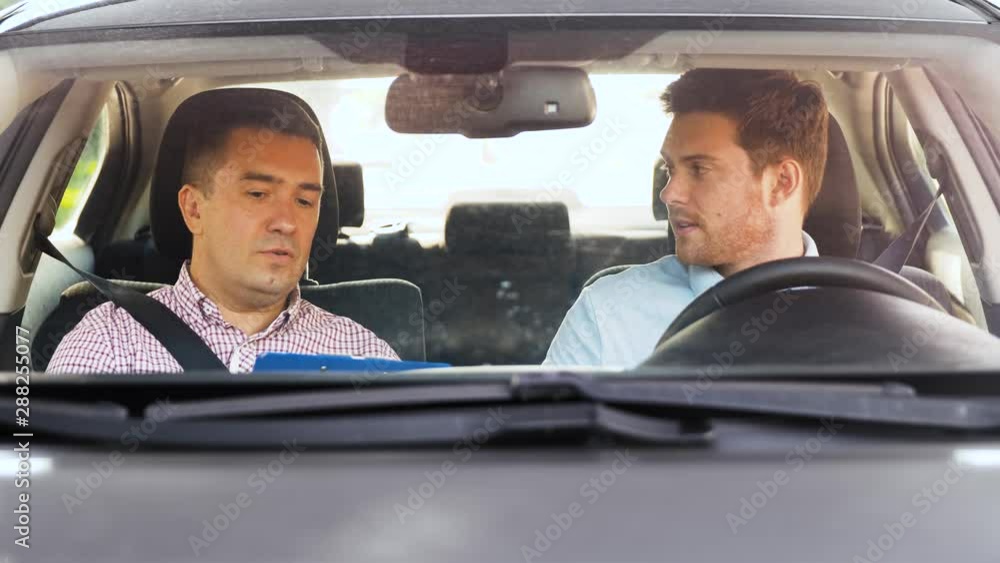 driver courses, exam and people concept - man and driving school instructor with clipboard talking and shaking hands in car driver courses, exam and people concept - man and driving school instructor with clipboard talking and shaking hands in car