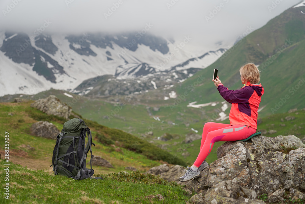 Portrait of woman taking a picture at the beautiful mountains background.
