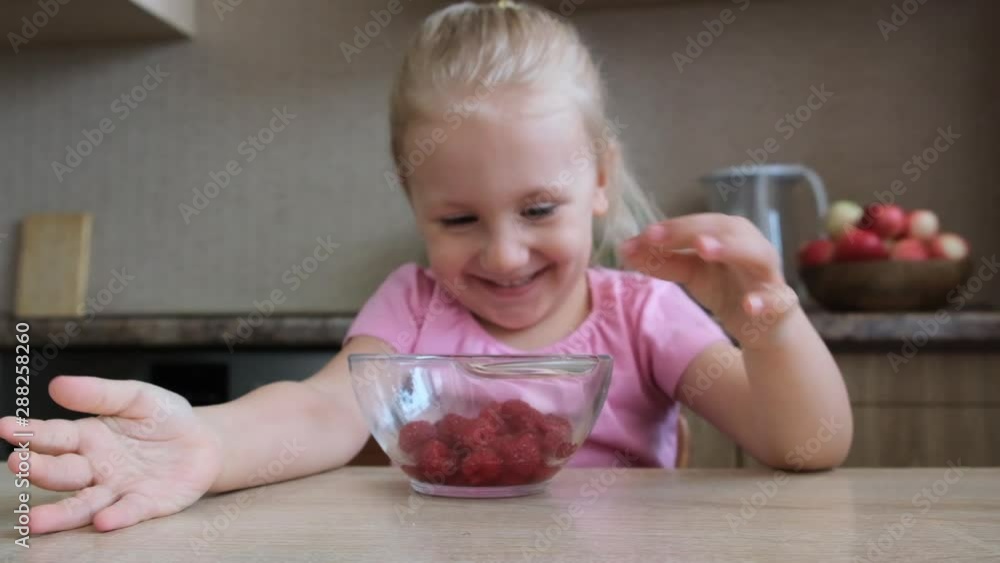 Cute little child girl portrait funny eating red raspberries putted on fingers Cute little child girl portrait funny eating red raspberries putted on fingers