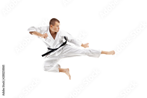 man exercising karate, kick in the air against white background