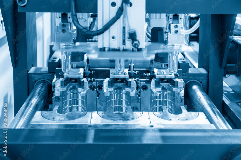 The blowing mould operation of PET bottles drinking water container manufacturing processing in the light blue scene. The plastic drinking water bottle manufacturing processing by blow mould machine. The blowing mould operation of PET bottles drinking water container manufacturing processing in the light blue scene. The plastic drinking water bottle manufacturing processing by blow mould machine.