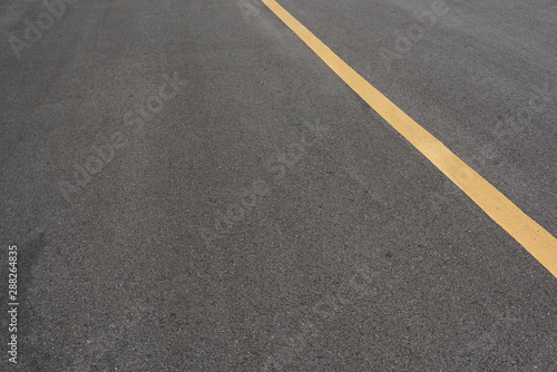Low angle view of a yellow paint slash on black asphalt road