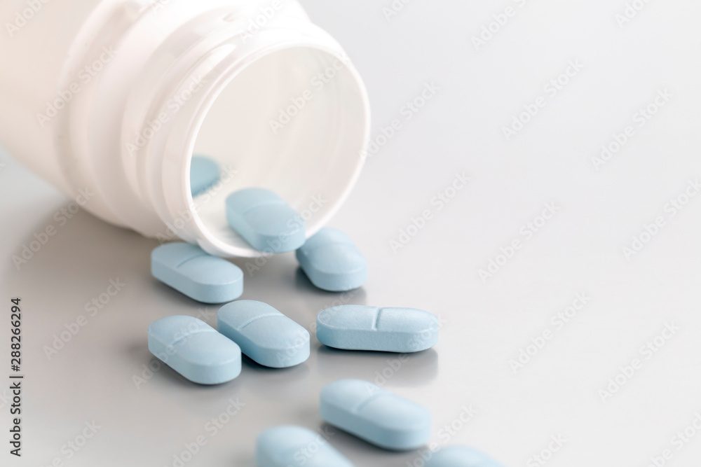 a close-up of a tablet bottle with a few blue antibiotic pills. a close-up of a tablet bottle with a few blue antibiotic pills.