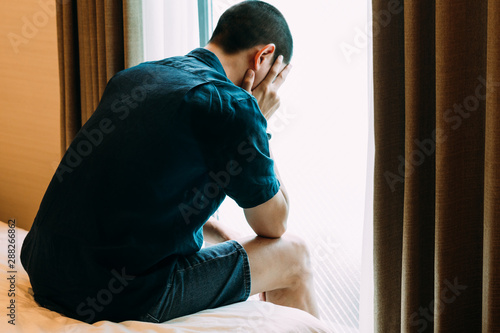 PTSD Mental health concept - Depressed Man with Problems sitting alone head in hands on the bed and Crying. Psychological trauma, Erectile, Frustration, Miserable, .Despair, Men health concept. photo