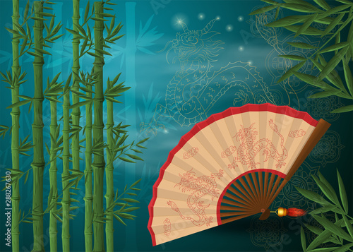 Chinese fan with dragons lies among bamboo thickets