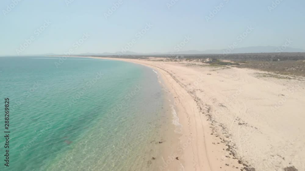 Forward drone shot above clear ocean waves crashing on a mexican sandy beach, on a sunny day Forward drone shot above clear ocean waves crashing on a mexican sandy beach, on a sunny day