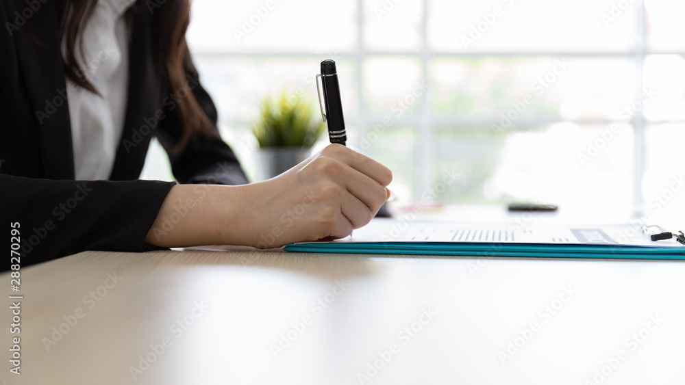 Φωτογραφία Close up Hand of Businesswoman signs, writing the documents on in desk at office building with natural light