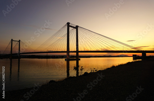 suspension bridge over river at sunset