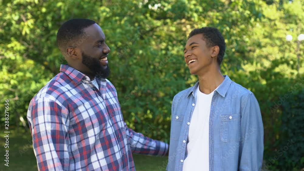 Delighted black men giving high five, happy brothers enjoying time together Delighted black men giving high five, happy brothers enjoying time together