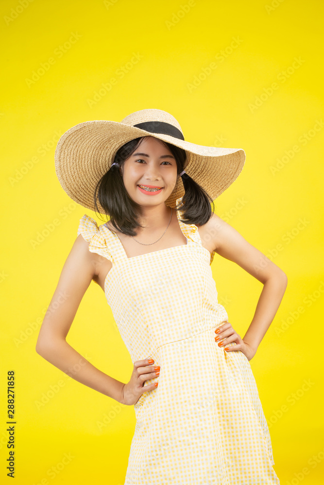 A beautiful, cheerful young woman with a big hat on a yellow background. A beautiful, cheerful young woman with a big hat on a yellow background.