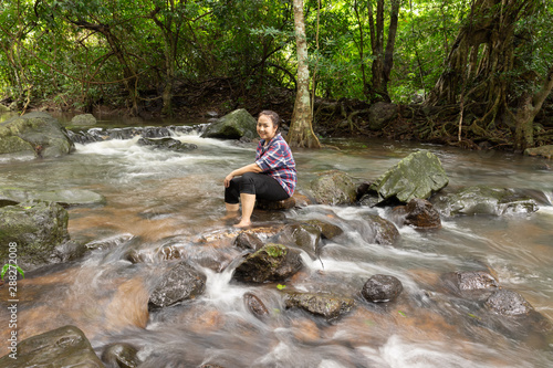 Asian women be smile sitting relaxing and enjoying view in waterfall in greens jungle. Traveling along mountains and rain forest, freedom and active lifestyle concept. Asia, Thailand