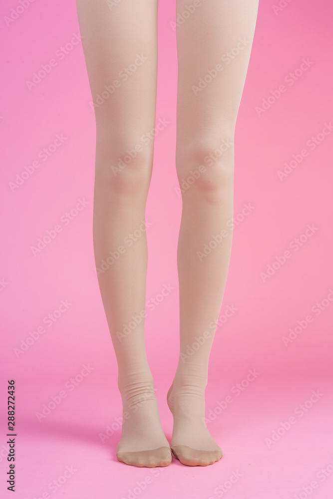 Slender legs, beautiful woman wearing stockings standing on a pink background. Slender legs, beautiful woman wearing stockings standing on a pink background.