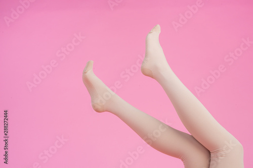 Slender legs, beautiful woman wearing stockings on a pink background. © artit