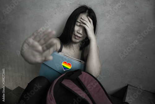 respect for homosexual and anti sexual discrimination campaign. Young beautiful depressed and scared Asian student woman with gay flag on her backpack photo