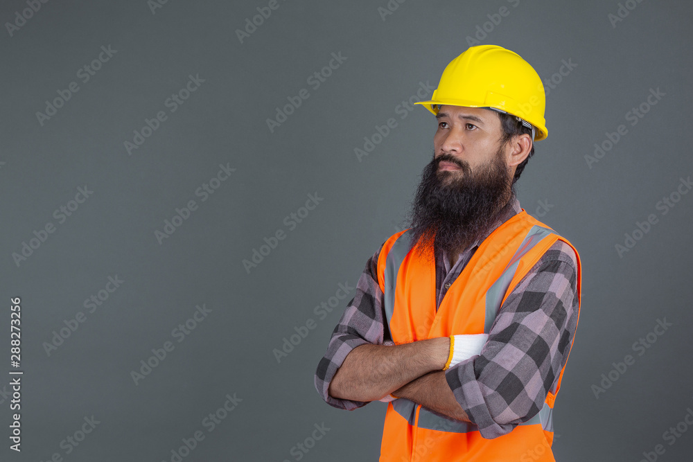 An engineering man wearing a yellow helmet wearing white gloves showed a gesture on a gray background. An engineering man wearing a yellow helmet wearing white gloves showed a gesture on a gray background.
