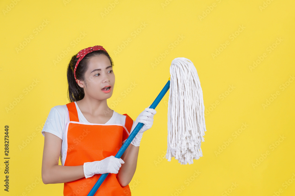 Cleaning concept. A beautiful woman with a cleaning device on a yellow background.