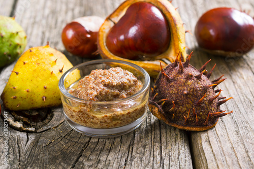 medicine and cosmetics raw ingredient: alcohol tincture from horse chestnuts on old wood table background