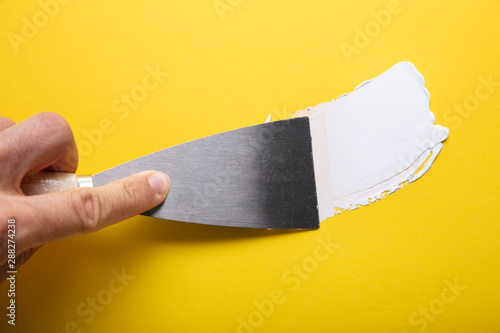 Painter Puttied Yellow Wall With Paint Trowel photo