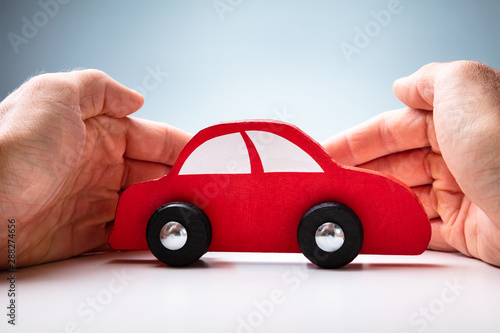 Businessman's Hand Protecting Red Toy Car