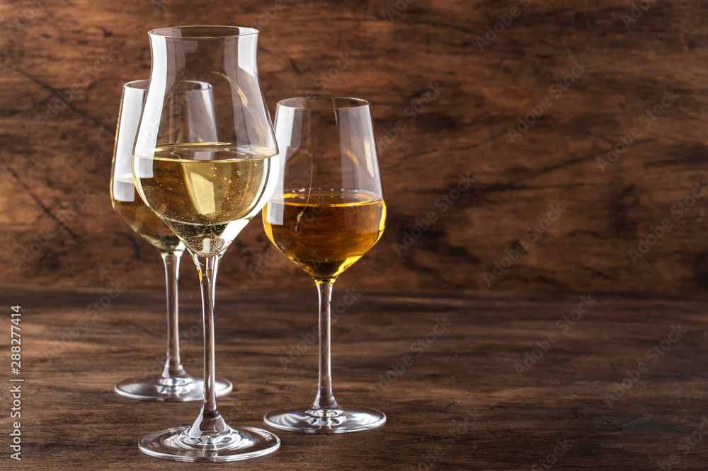 White wine set. Wine tasting, the most popular varieties of white wines in wine glasses on vintage wooden table in rustic style, selective focus White wine set. Wine tasting, the most popular varieties of white wines in wine glasses on vintage wooden table in rustic style, selective focus