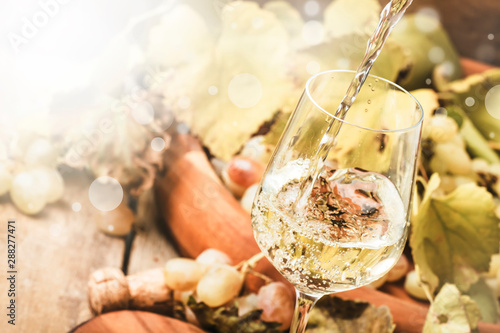 White wine being poured into a glass, vintage wood background, selective focus photo
