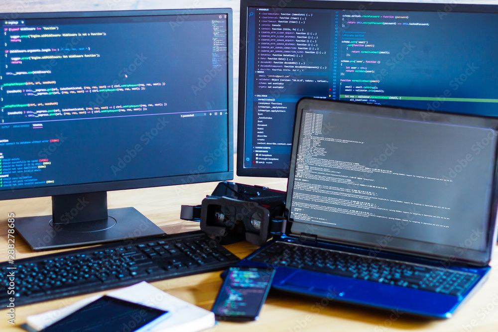Foto de Multiple computer screens with program code are on office table ...