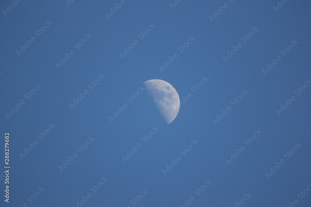 The Moon in the Day time with Blue sky background The Moon in the Day time with Blue sky background