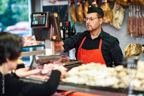 Butcher attending a customer in a butcher's shop photo