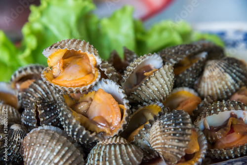 Steamed blanched cockles with Thai seafood dipping sauce and lettuce in the white dish.