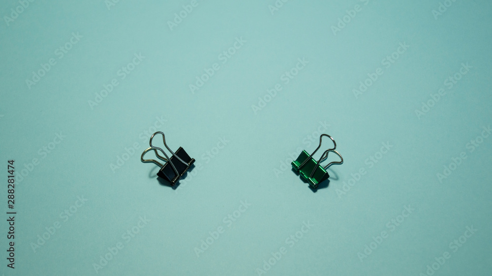 Black and green paper clip on a blue background. Black and green paper clip on a blue background.