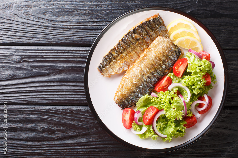 Healthy food grilled mackerel fillet with lemon and fresh vegetable salad close-up on a plate. Horizontal top view Healthy food grilled mackerel fillet with lemon and fresh vegetable salad close-up on a plate. Horizontal top view