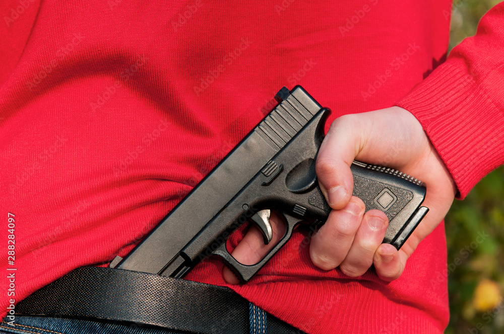 armed with a gun. hides the gun by the belt. use of firearms Stock