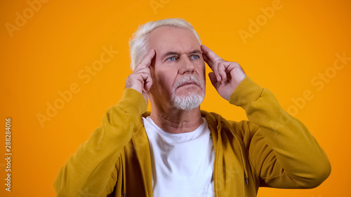 Fotografía Senior male telepathist touching temples, trying to read thoughts, mentalist