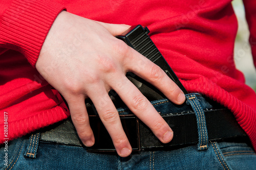 armed with a gun. hides the gun by the belt. use of firearms photo